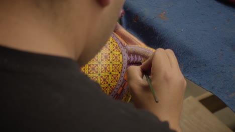 Junge-Handwerker,-Die-An-Traditionellen-Mexikanischen-Handwerk-Arbeiten,-Malen-Eine-Alebrije-Figur-In-Einer-Werkstatt-In-Oaxaca