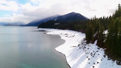 Drone-Footage-showcasing-snow-in-Lake-Kachess-with-mountains-in-the-background-in-Washington-State