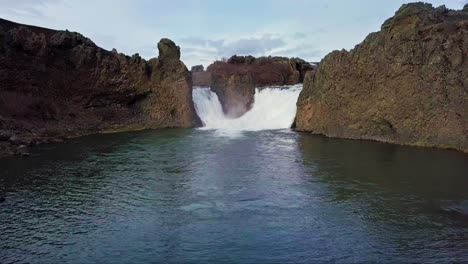 Twin-waterfalls-gushing-into-pond-in-Iceland-surrounded-by-rocky-terrain