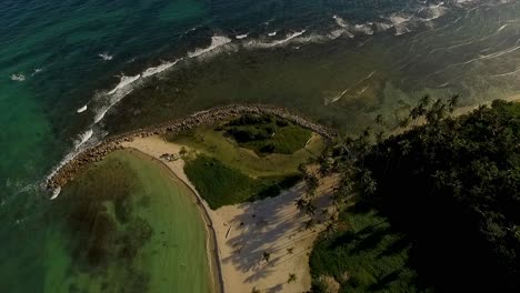 Overhead-drone-shot-slowly-descending-down-the-Miami-Beach-peninsula-as-waves-crush-at-its-shores-in-Itea,-in-Central-Greece