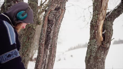 Norweger-Mit-Kopfhörern,-Der-Im-Winter-Alte-Baumrinden-überprüft