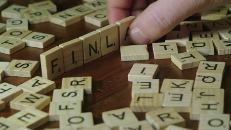 Scrabble-tiles-in-closeup:-Word-FINLAND-is-made-by-male-right-hand