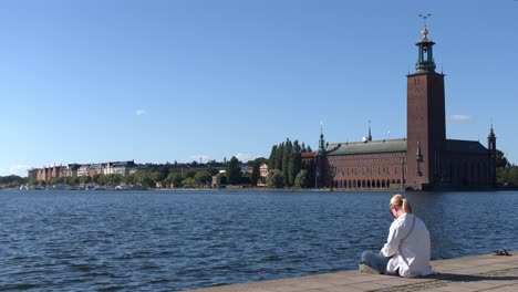 Stockholm:-a-girl-sitting-by-the-sea-in-front-of-Stockholm-city-hall