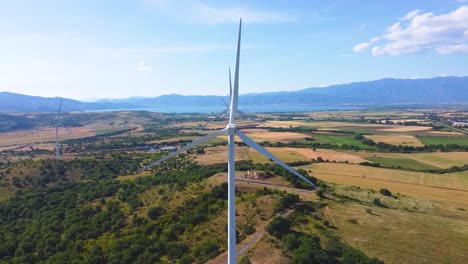 Aerial-Crane-shot-of-Wind-Turbines-Turning-in-Doirani-Kilkis-Greece,-Lake-in-Background