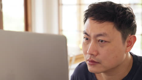 Close-up-of-Asian-man-looking-on-computer-screen