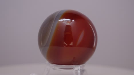 Agate-Crystal-mineral-sphere-rotating-on-a-turn-table-in-front-of-a-white-background