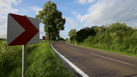 Motociclista-Circulando-Por-Una-Carretera-Curva-Con-Señales-Direccionales-En-Un-Día-Soleado