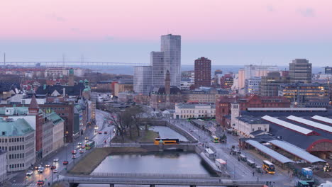 Dämmerungsdrohne-über-Kanälen-In-Der-Nähe-Des-Hauptbahnhofs-Von-Malmö,-Öresundbrücke-Am-Horizont