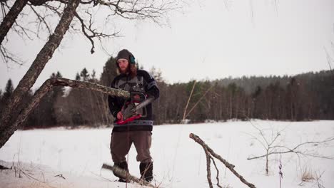 Man-With-Chainsaw-Cutting-Trees-During-Winter