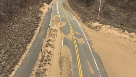 Forward-movement-along-a-winterized-road-covered-in-sand-from-high-winds