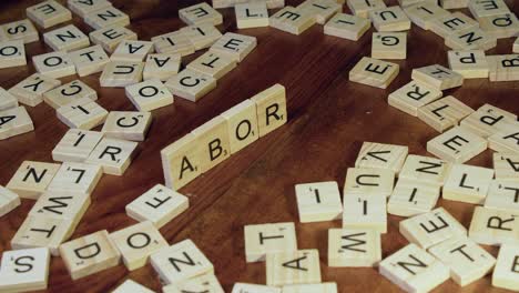 Right-hand-places-Scrabble-letter-tiles-on-edge-to-form-word-ABORTION
