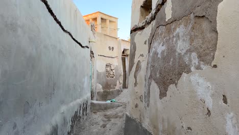 walking-in-desert-city-old-town-tropical-climate-ruins-of-mudbrick-house-Arabian-culture-traditional-architecture-design-winding-lane-windcatcher-ancient-natural-ventilation-air-flow-historical-house