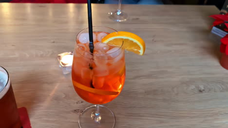Cocktail-Nahaufnahme-Auf-Holztisch,-Herzhaftes-Getränk-Mit-Einer-Orangenscheibe-In-Frischem-Eis-Verschmolzen
