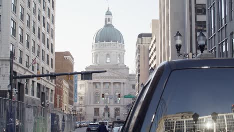 View-down-the-road-in-Indianapolis,-Indiana-of-the-Indiana-state-capitol-building-with-vehicle-traffic-and-video-tilting-up