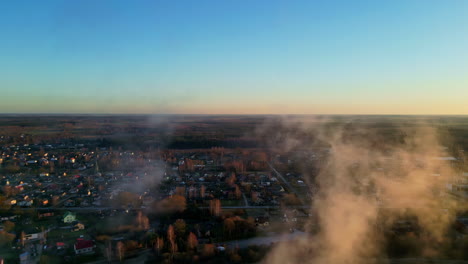 Aerial-gradient-sunset-smoke-below-American-city-drone-horizon-skyline-houses-and-fog-clouds-like-a-flying-top-rotating-view