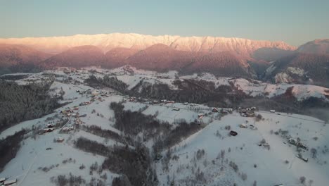 Aerial-shot-of-Piatra-Craiului-Mountains-at-sunrise-with-snow-covered-village