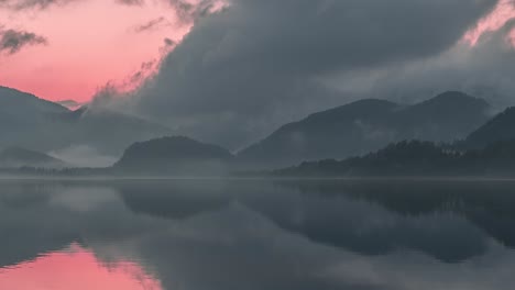 Schwere-Wolken-Am-Rosafarbenen-Abendhimmel-Spiegeln-Sich-Im-Spiegelglatten-Wasser