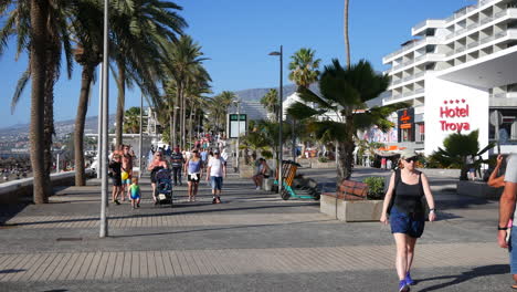 Tourists-walking-along-the-beach-coast-road-in-Las-Americas-in-Tenerife-next-to-the-Hotel-Troya