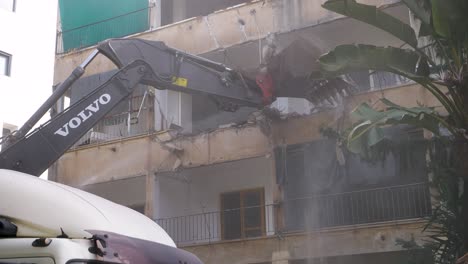 Debris-falling-from-a-balcony-as-a-heavy-excavator-attempts-to-tear-it-down