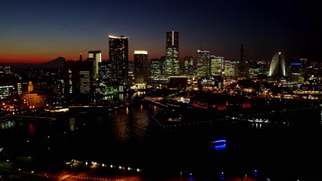 Twilight-cityscape-with-illuminated-buildings-along-the-river,-clear-sky