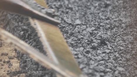 Close-Up-Shot-of-Hot-Gravel-Being-Raked-Over-Pothole