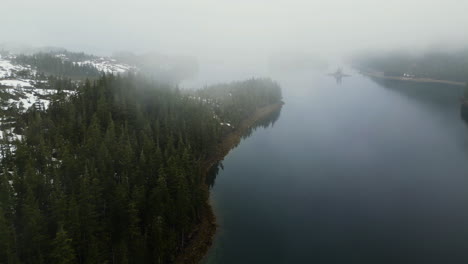 Drone-shot-around-foggy-forest-and-over-tranquil-sea,-misty,-spring-day-in-Alaska