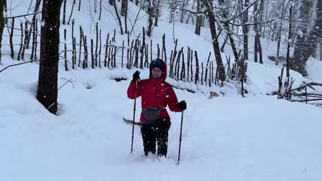 Hard-walking-in-heavy-snow-in-winter-in-Hyrcanian-forest-winter-landscape-snowfall-in-wonderful-nature-rural-village-countryside-trekking-pole-red-color-jacket-and-black-pant-person-hiking-alone-iran