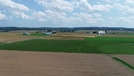 An-Aerial,-Slow-Rotation,-of-Farmlands,-With-Green-Fields-and-Plowed-Fields-on-a-Partially-Sunny-Day
