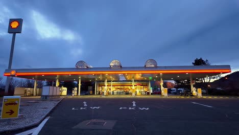 Estación-De-Gasolina-Vacía-E-Iluminada-A-Primera-Hora-De-La-Tarde-Con-Las-Bombas-De-Combustible-Y-La-Tienda-Al-Fondo