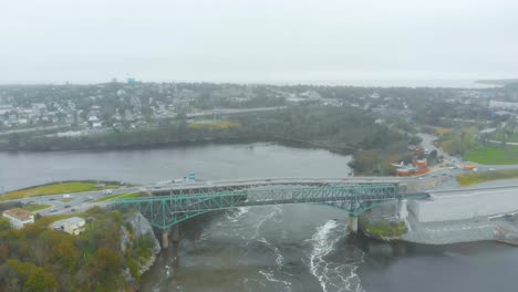 An-Aerial-shot-of-the-reversing-falls-bridge-with-cars-passing-overtop-on-a-cloudy-day