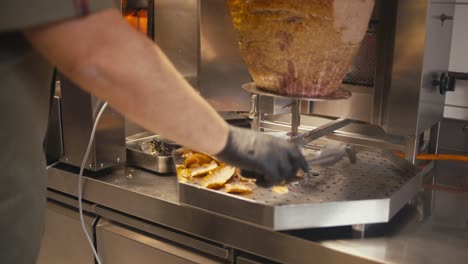 Chef-slicing-doner-kebab-meat-on-a-rotating-spit-in-a-fast-food-shop,-close-up