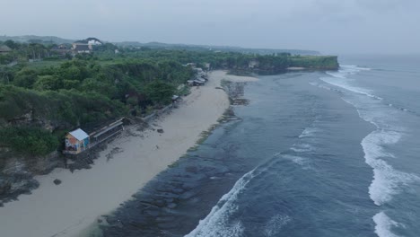 Aerial-drone-flying-over-tropical-Balangan-Beach-in-Uluwatu-Bali-Indonesia-with-breaking-waves