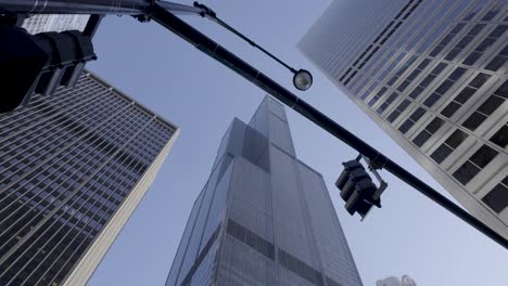 Blick-Nach-Oben-Auf-Die-Wolkenkratzer-Von-Chicago-Vor-Einem-Klaren-Blauen-Himmel,-Mit-Straßenlaterne-Und-Teilweisen-Reflexionen