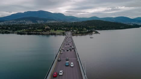 Forward-shot-of-a-busy-bridge-with-mountains-and-cityscape-at-background