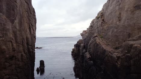 Drone-footage-flying-between-two-small-cliffs-out-over-the-ocean-in-Donegal,-Ireland