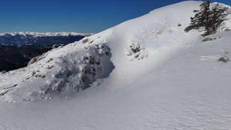 Snow-covered-slope-with-footprints-in-Bucegi-Mountains,-view-towards-Iezer-Papusa-and-Piatra-Craiului