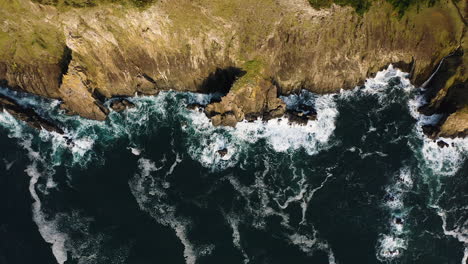 Top-down-aerial-push-in-towards-sheer-cliffs-of-Oregon-Coast-along-Pacific-Ocean