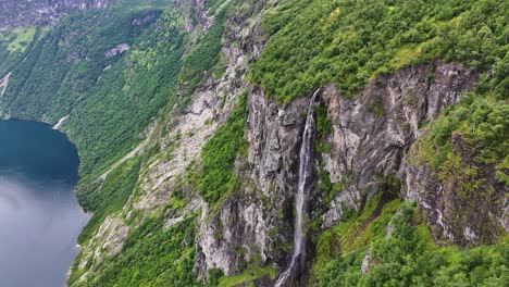Luftaufnahme-Von-Wasserfall-Und-Klippe-über-Dem-Fjord-In-Der-Landschaft-Norwegens,-Geirangerfjord,-Drohnenaufnahme,-Sieben-Schwestern-Wasserfall