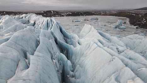 Dramatic-crevasses-of-Vatnajokull-glacier-in-Iceland,-low-aerial-dolly-in-on-overcast-day