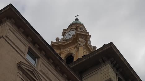 Clip-Panorámico-Mirando-Hacia-Arriba-A-La-Torre-Abovedada-De-La-Iglesia-Con-Un-Reloj-Ornamentado-Y-Aleros-Decorativos-Del-Techo