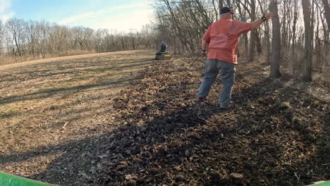 Man-picking-up-sticks-from-rototilled-soil-to-prepare-a-deer-food-plot-for-planting-in-Midwest-in-early-Spring