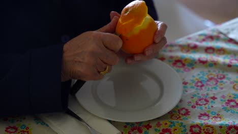 Hände-Einer-Alten-Frau-Schälen-Eine-Orange-Mit-Einem-Messer-In-Einem-Zug,-4k