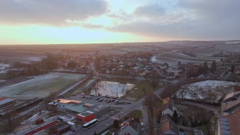 Vista-Panorámica-Sobre-La-Ciudad-Y-El-Lago-Congelado-Con-Gente-Patinando-Sobre-Hielo---Disparo-De-Drone