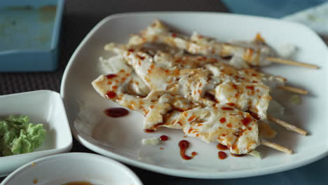 Teriyaki-chicken-skewers-on-plate-at-restaurant,-slow-motion-shot-at-60-fps