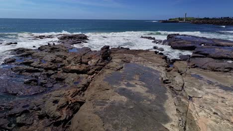 Aerial-over-rocks-and-the-crashing-surf-towards-the-light-houses-at-Wollongong-Harbour