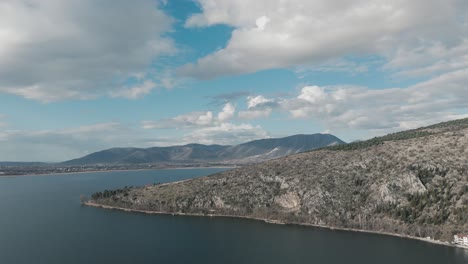 A-rotating-drone-shot-of-a-mountain,-warm-weather,-flying-above-a-dreamy-lake,-4K-video,-European-winter-nature,-beautiful-landscape,-white-scenic-clouds