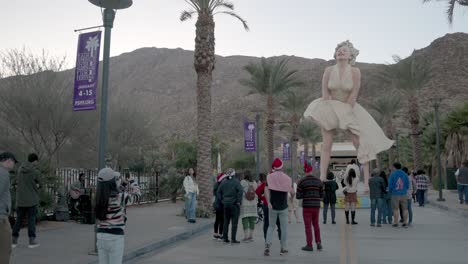 Marilyn-Monroe-statue-in-Palms-Springs,-California-with-tourists-and-video-panning-right-to-left-wide-shot
