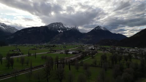 Aerial-establishing-above-leafless-trees-in-rows-on-farm-fields-to-base-of-mountains-in-Walensee-Switzerland