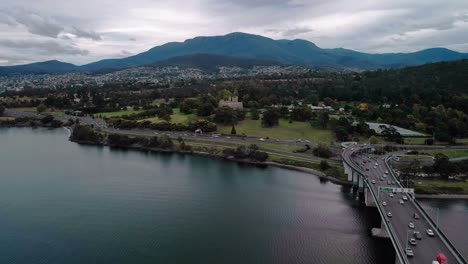 Toma-Aérea-De-Montañas-Al-Fondo-Con-La-Ciudad-Y-El-Puente-En-Primer-Plano