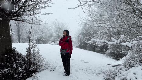 Eine-Frau,-Die-In-Den-Himmel-Schaut,-Bei-Starkem-Schneefall-Im-Winter-In-Einer-Waldnaturlandschaft,-Wundervolle-Malerische-Weitsicht-Auf-Epischen-Schnee,-Eiskalter-Tag-Im-Iran,-Parrotia-Persica-In-Schneebedeckten-Hügeln,-Bäume-Im-Hintergrund